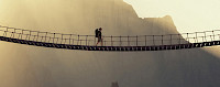 Mann mit Rucksack geht über eine Hängebrücke - © 